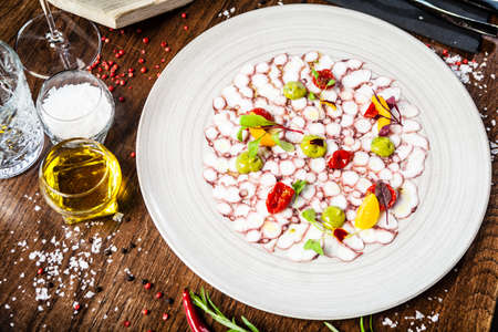 Octopus carpaccio. Spinach cream, cherry tomatoes. Delicious healthy Italian traditional food closeup served for lunch in modern gourmet cuisine restaurant.の写真素材