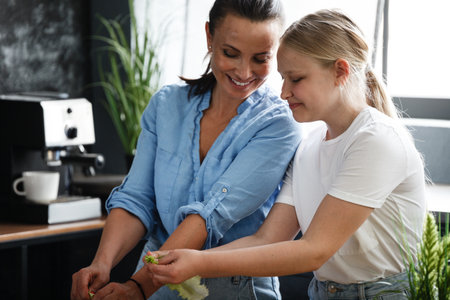 Healthy food at home. Happy family, mother and daughter are preparing salad. Woman and teenage girl are cutting vegetables in the kitchen.の写真素材