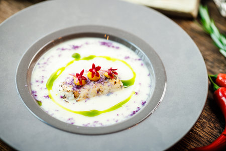 Jerusalem artichoke-almond cream soup with scallop roll. Leek, almond milk, garlic. Delicious healthy Jewish traditional food closeup served for lunch on a table in modern gourmet cuisine restaurantの写真素材