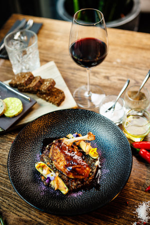 Corn chicken supreme. Beluga lentils, Old Ammerlander cheese, mini zucchini, red wine sauce. Delicious healthy traditional food closeup served for lunch in modern gourmet cuisine restaurantの写真素材