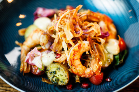 Warm salad with Argentinian king prawns. Almond potato, mini romaine lettuce, carrot, cherry tomato, pesto, black root chips, caramelized walnut, beet balsamic. Food served in modern restaurantの写真素材