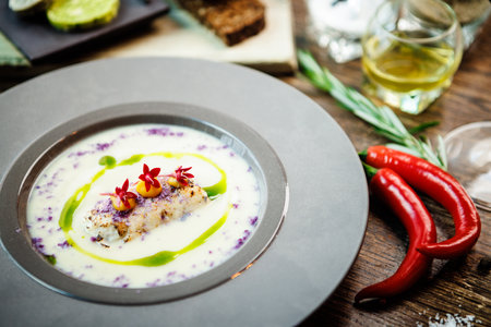 Jerusalem artichoke-almond cream soup with scallop roll. Leek, almond milk, garlic. Delicious healthy Jewish traditional food closeup served for lunch on a table in modern gourmet cuisine restaurantの写真素材