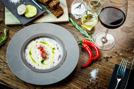 Jerusalem artichoke-almond cream soup with scallop roll. Leek, almond milk, garlic. Delicious healthy Jewish traditional food closeup served for lunch on a table in modern gourmet cuisine restaurantの写真素材