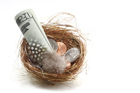 savings and personal dreams signified by a nest egg filled with dollar bills and coins; white backgroundの写真素材