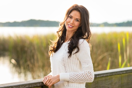 Smiling, pretty brunette on Fall nature walk with tall grass and lake の写真素材
