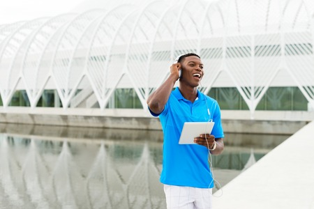 Black, African American college student wearing headphones and listening to music on a digital tablet computerの写真素材