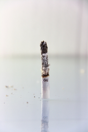 hand made cigarette burning in front of white backgroundの写真素材