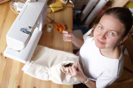 Beautiful woman working in her home with her little cute girl and cutting dress patternsの写真素材