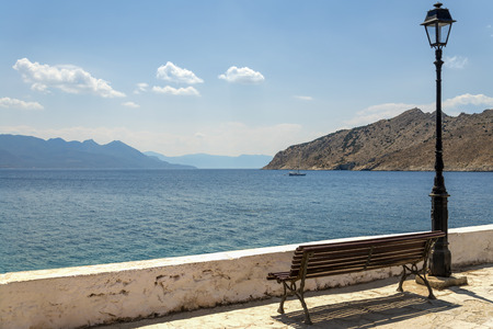 Bench under a street lamp on the promenade overlooking the sea and mountainsの写真素材
