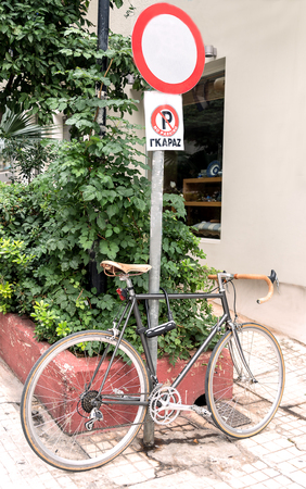 grey bike standing near a stop sign near in the parkの写真素材