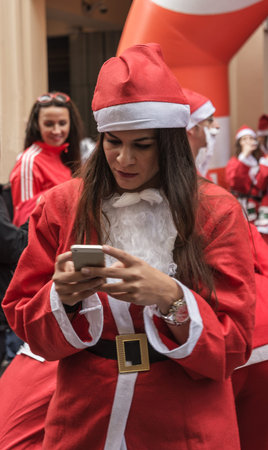 Athens, Greece - December 7, 2014: Marathon "Santa Run" - Santa Claus girl with mobile phoneのeditorial素材