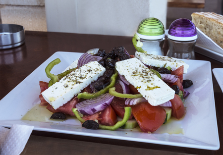 traditional greek salad with feta and olives on the tableの写真素材