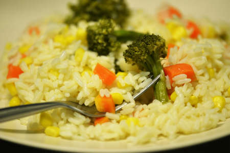 rice with carrots, corn and broccoli on a plateの写真素材