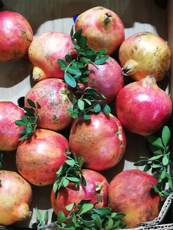 much red pomegranates with green leaves in a boxの写真素材