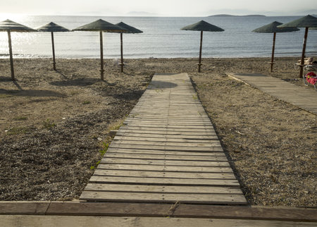 wooden walkway and umbrellas on the summer beachat morningの写真素材