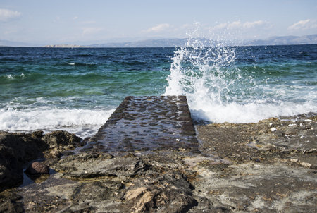 Mediterranean landscape - sea wave hitting a stone pier. Greece, island Aeginaの写真素材