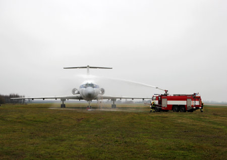 large aircraft being sprayed with water by a fire engine at an airfieldの写真素材