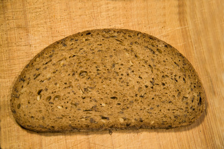 A slice of black bread on a cutting board - close-up, isolated on a white background