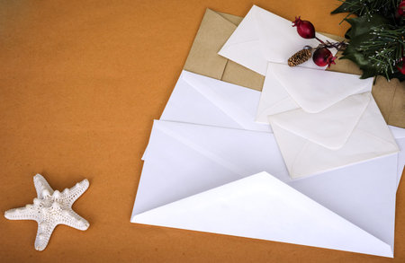 White greeting envelopes and Christmas decorations on a sand background
