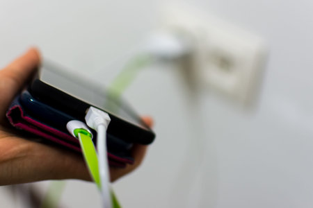 Woman holding mobile phone and trying to plug in charger