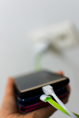 Woman holding two mobile phones that are chargingの写真素材