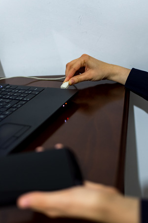 Young woman using hard drive disk to buckup her data during the working dayの写真素材