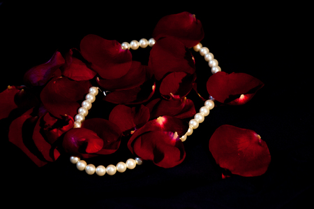 Pear necklace and peatals of the rose on the black backgroundの写真素材