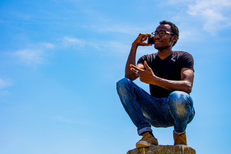 Young black business man with glasses speaking on the phoneの写真素材