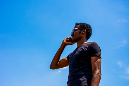 Young black business man with glasses speaking on the phoneの写真素材