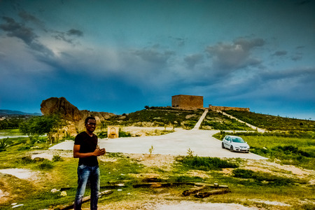 Black man standing in front of ruined building from the Frig time that is on the coast of Emre lakeの写真素材