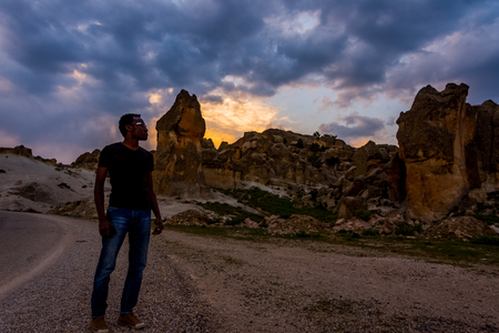 Between two Turkish cities Afyon and Eskisehir there is Frig valley. Many ruins similar to ones in cappadocia are in that valley . The black man standing in front of them during the sunsetの写真素材