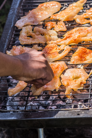 The man putting spiced chicken breast on the grill to make a lunch for family and friendsの写真素材