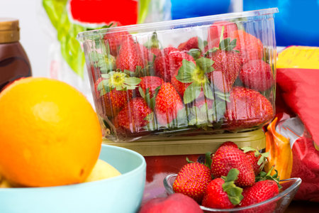 The mess on the kitchen table with fruits like strawberries and oranges and myny other things