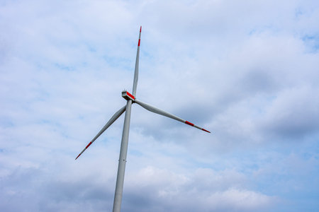 Windmill with the red stripes on a cloudy day ready for production of electricity