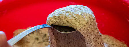 Taking dough of wheat and buckweat by spoon to cook fritters for the breakfast