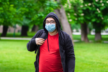 Man follow measures and wearing face mask against corona virus while he is walking in the park
