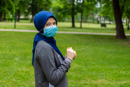 Modern muslim woman wearing surgical face mask fighting with corona virus