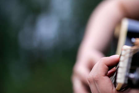 Closeup shot of girl's hand playing acoustic guitar outdoor.の写真素材
