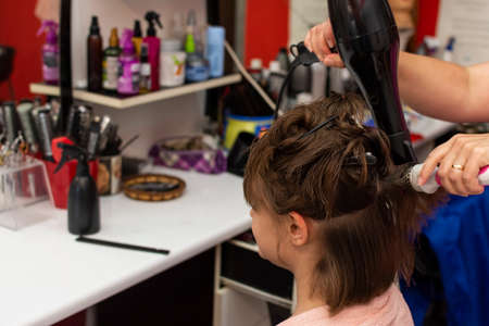 Beautiful teen girl at the hairdresser blow drying her short hairの写真素材