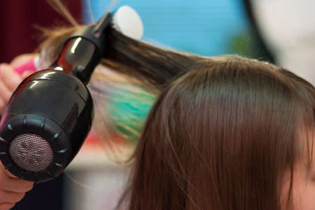 Beautiful teen girl at the hairdresser blow drying her short hairの写真素材