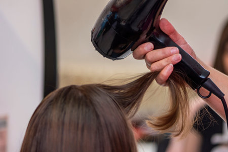 Beautiful teen girl at the hairdresser blow drying her short hair