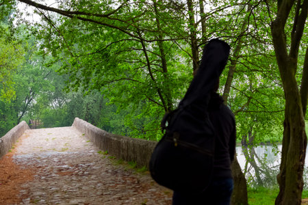 Young man carry guitar bag while walking through the forest