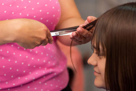 Professional female hairdresser cutting girls hair in salonの写真素材
