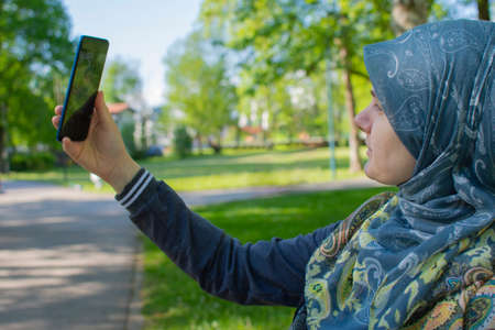 Muslim pregnant woman taking selfie in the park with smartphone. Memories of the pregnancy lifestyleの写真素材
