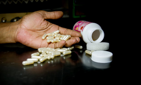 medicine capsule in hand and spilling out of a bottle.