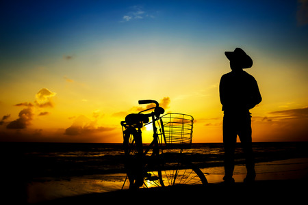 Man wore hats stood watch The sun rises in the morning at the beach.の写真素材