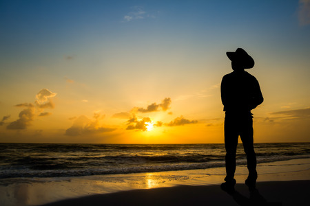 Man wore hats stood watch The sun rises in the morning at the beach.の写真素材