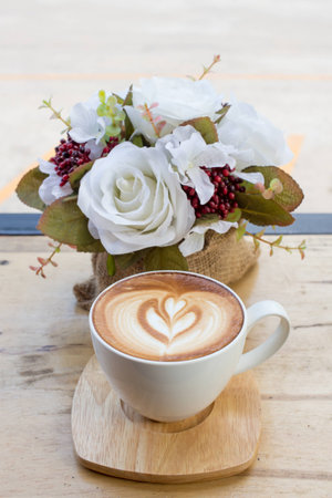 Cup of coffee on a table with flowersの写真素材