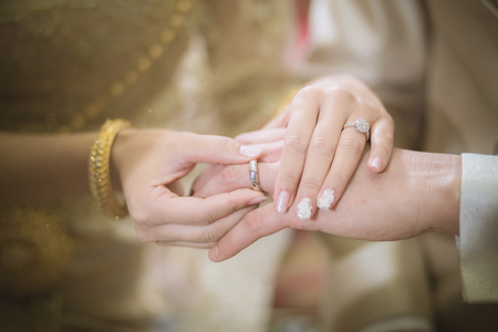 Thai groom wearing wedding ring for his brideの写真素材