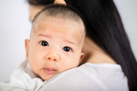 Asian woman holding her baby boy isolated over white backgroundの写真素材